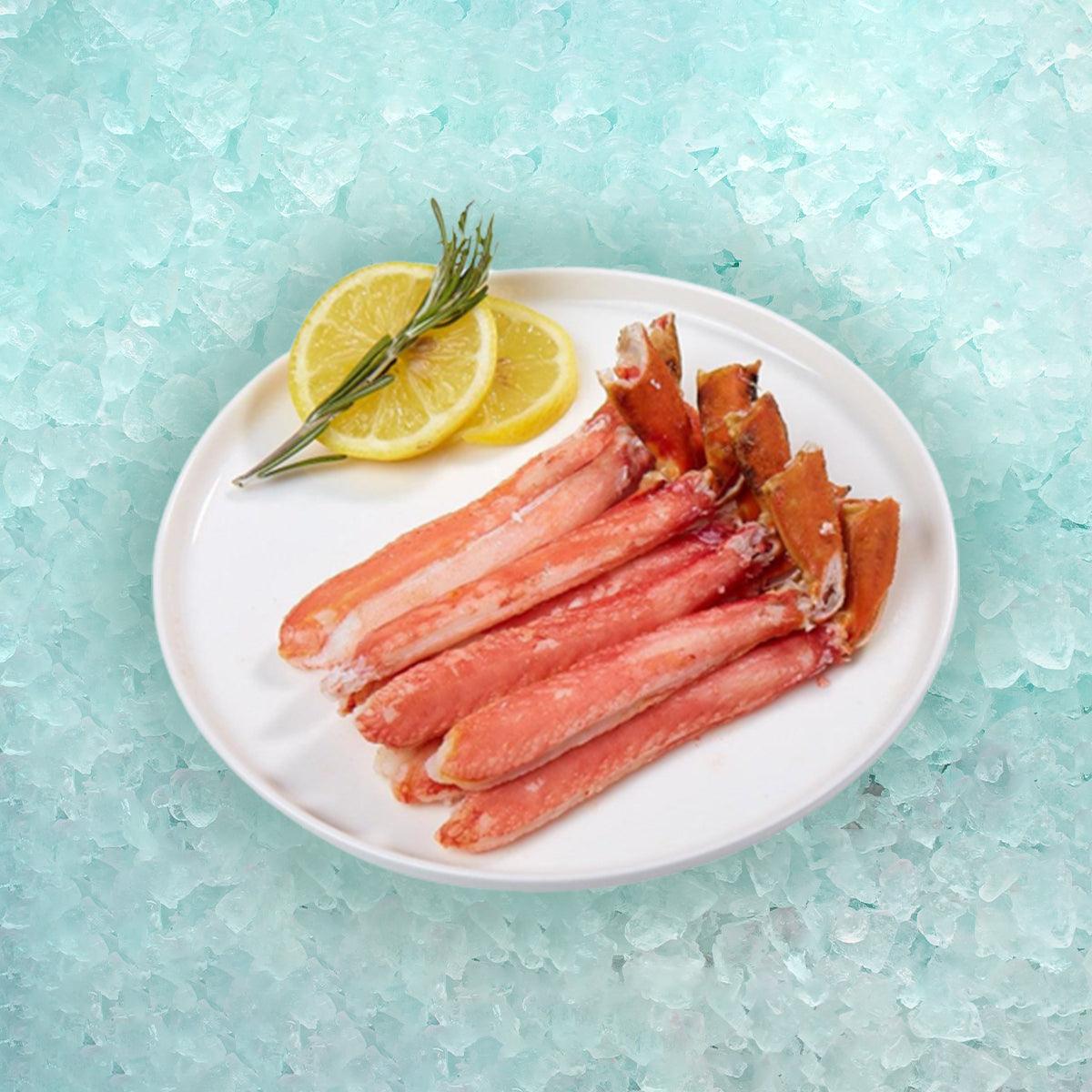 Cooked snow crab legs on white plate with lemon slices and rosemary