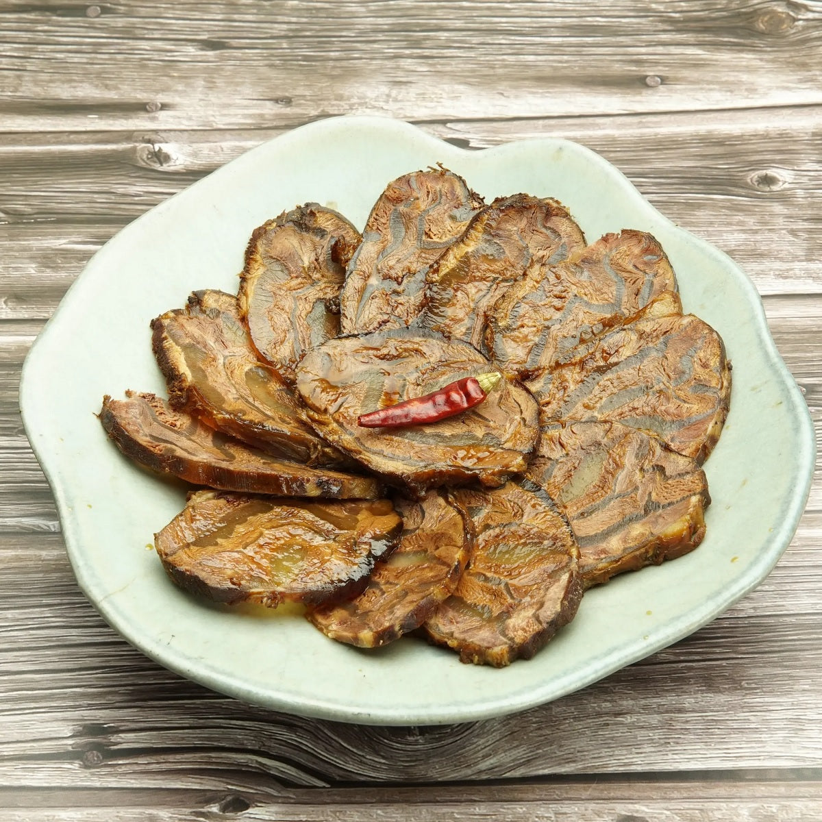 Braised beef shank in mala sauce, sliced pieces on a white plate