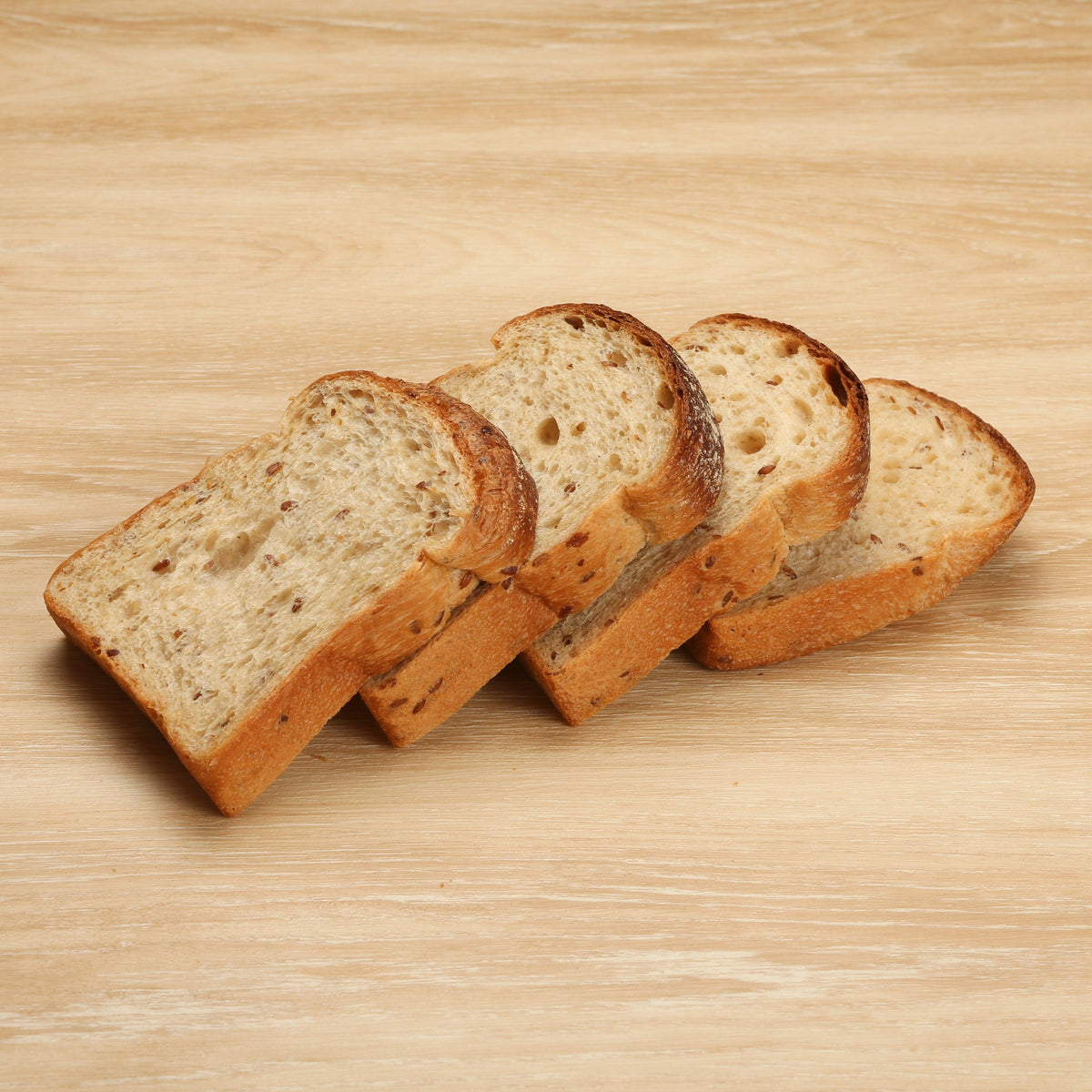 Sliced flaxseed grain bread loaf, several pieces laid out
