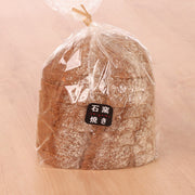 Rye grain bread loaf in clear bag, dark crust, round top with label