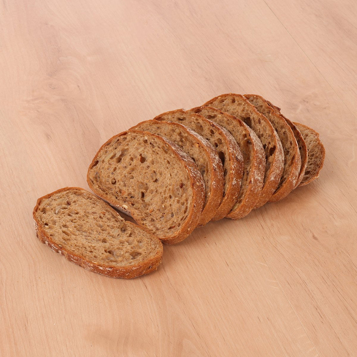 Sliced whole grain rye bread loaf, round slices fanned on wood surface