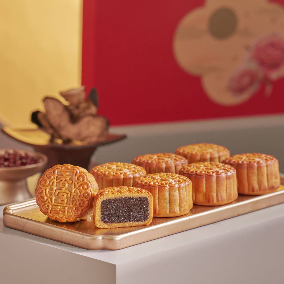 Assorted mooncakes with one cut piece, golden-brown crust, on serving tray