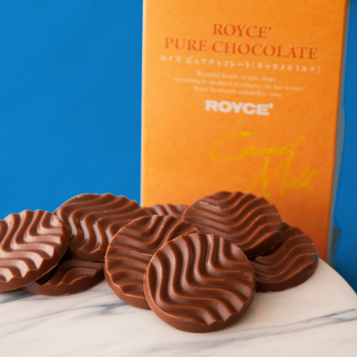 Heart-shaped caramel milk chocolates on white plate with chocolate box behind.