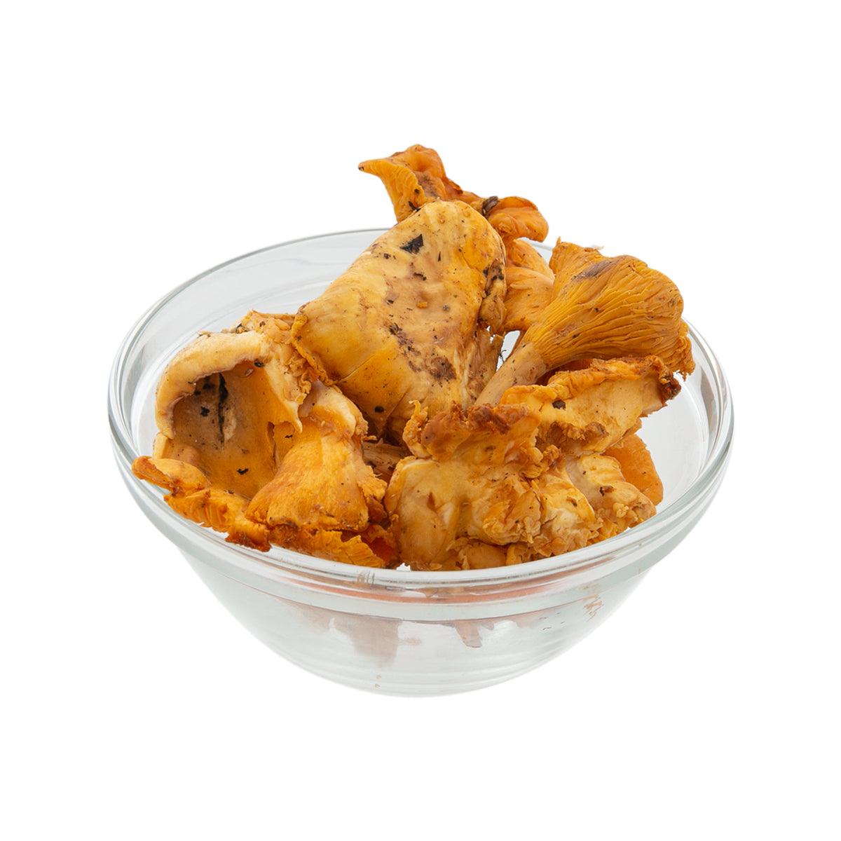 Fresh chanterelle mushrooms in clear glass bowl, orange-golden pieces