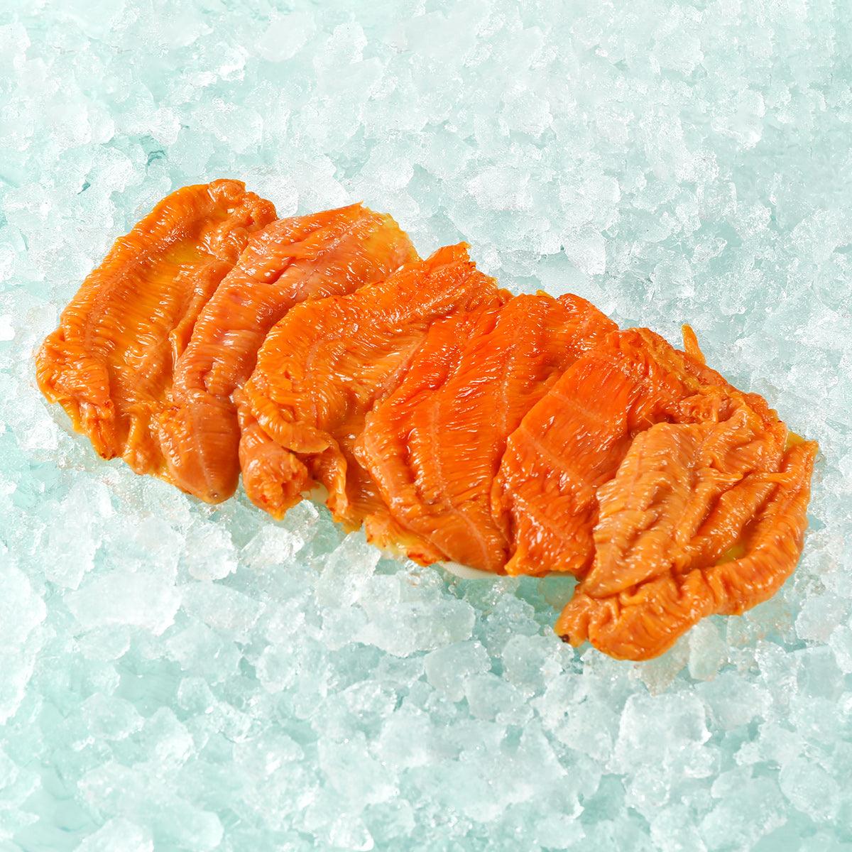 Previously frozen red sea cucumber meat, sliced orange-red portions on ice