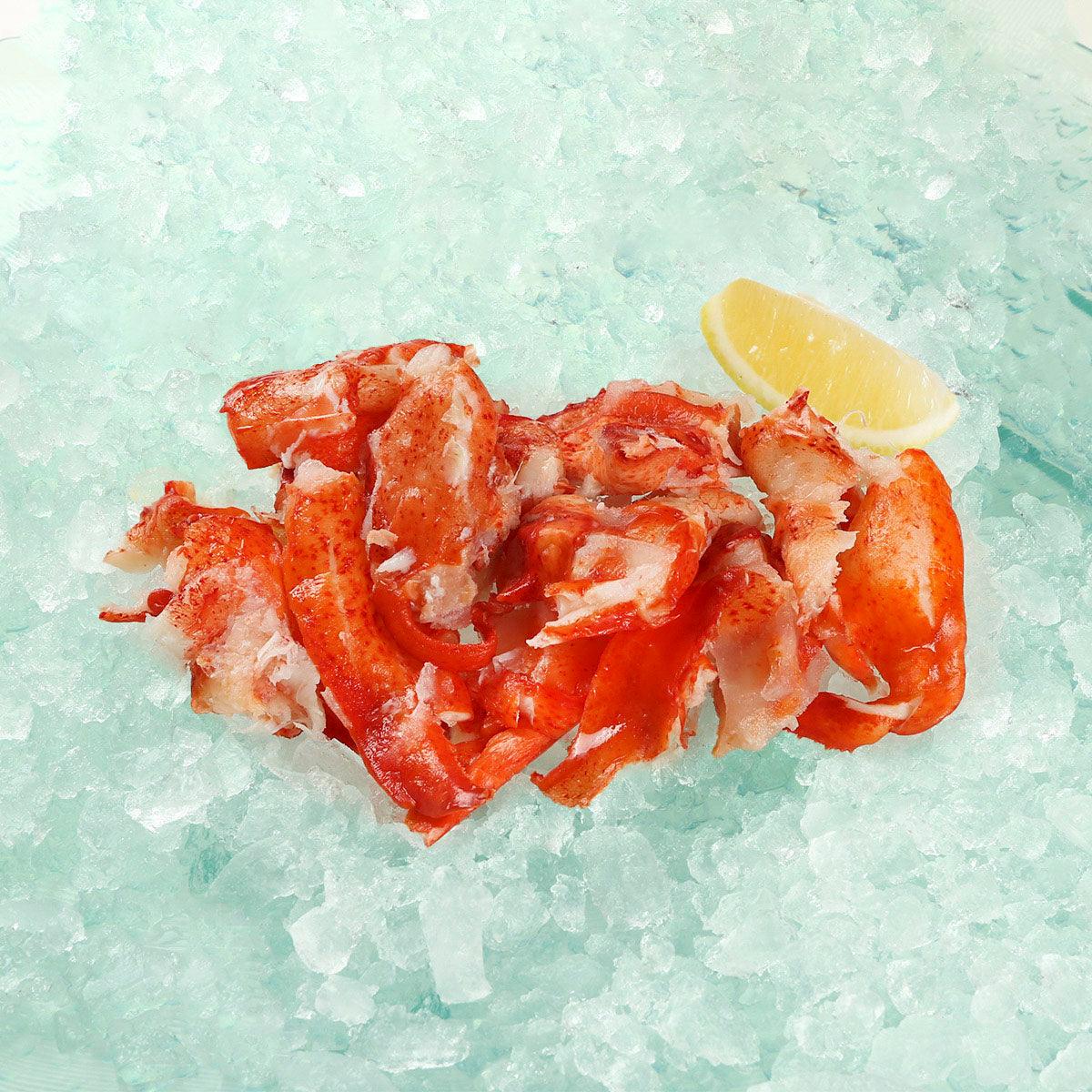 Fully cooked lobster meat, red-orange chunks with white meat flecks on ice