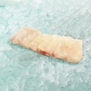 Giant grouper fish slice with pale flesh, raw portion on ice