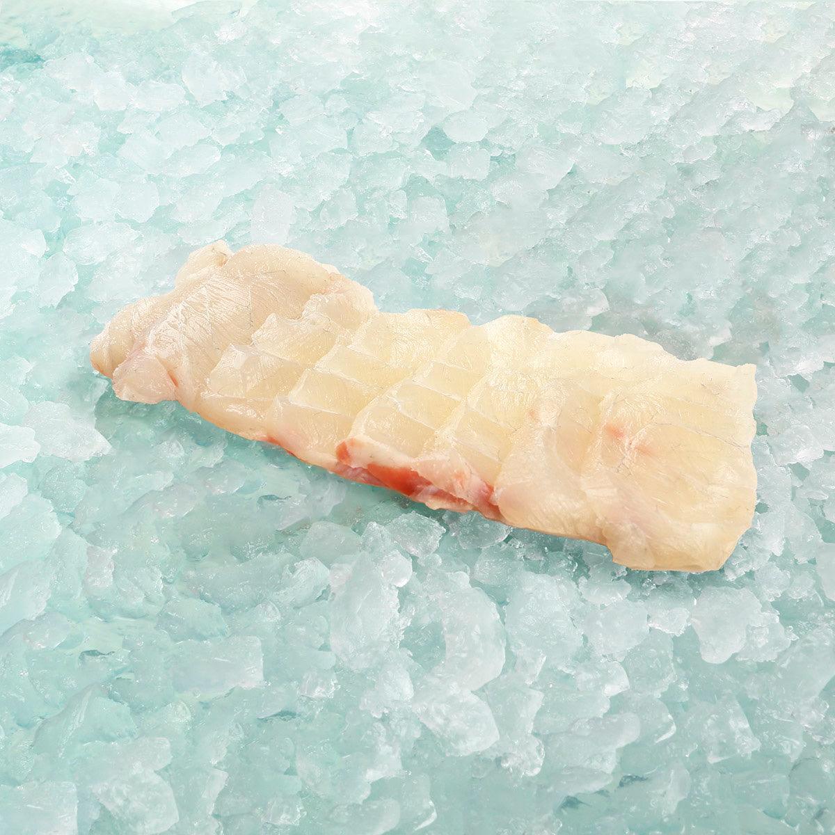 Giant grouper fish slice with pale flesh, raw portion on ice