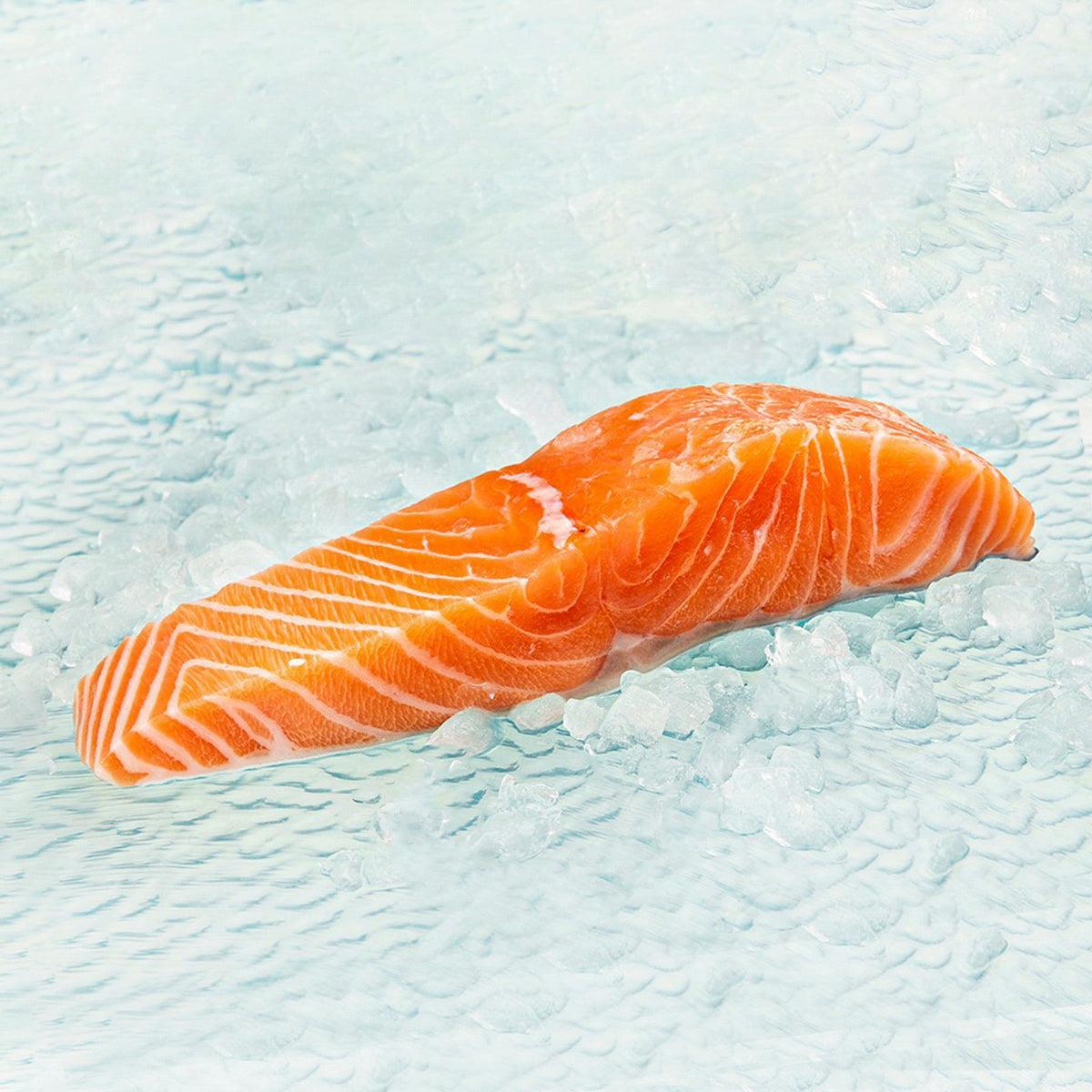 Chilled salmon kirimi slice, bright orange with white marbling, on ice