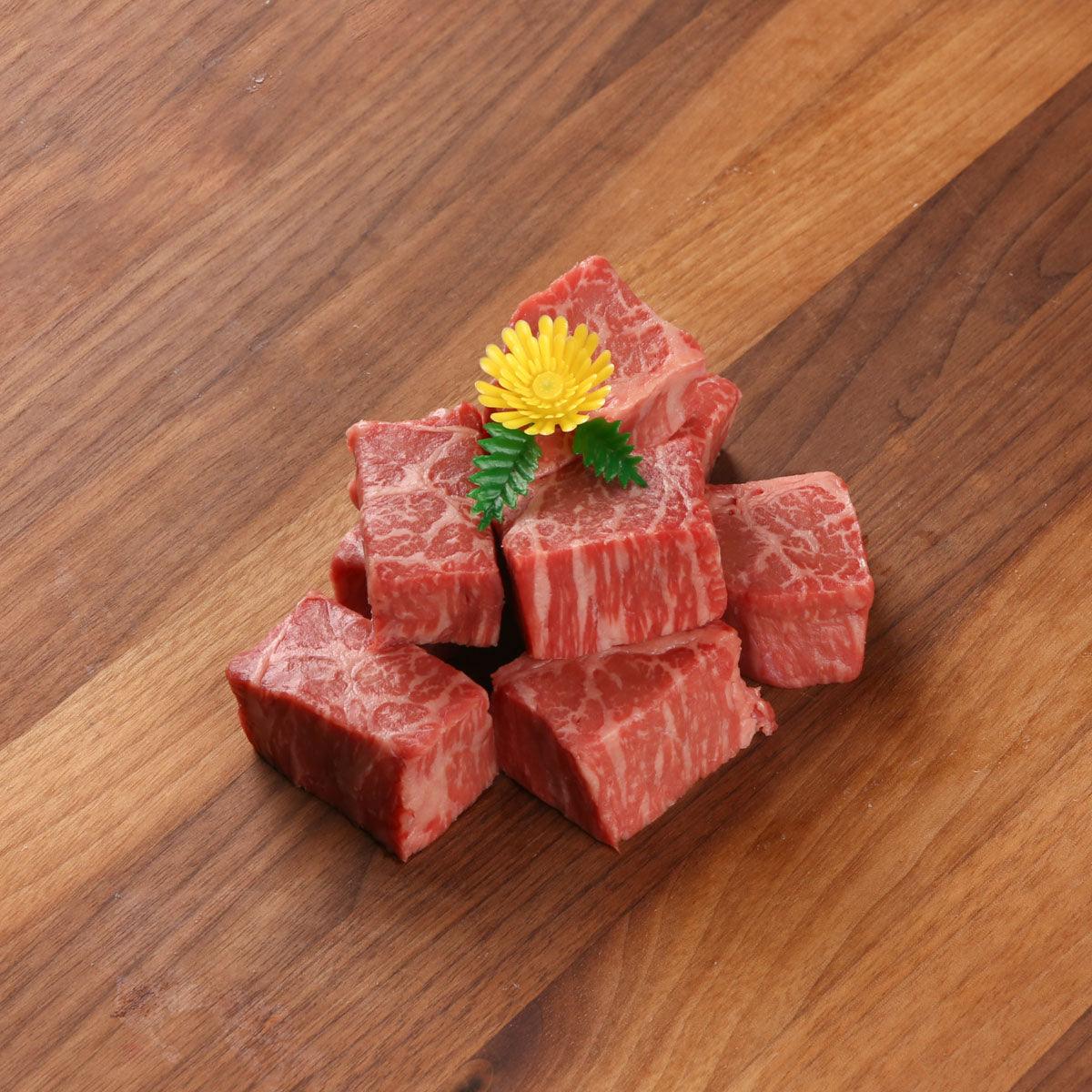 Marbled Wagyu beef cubes, red with visible fat marbling, garnished with herbs