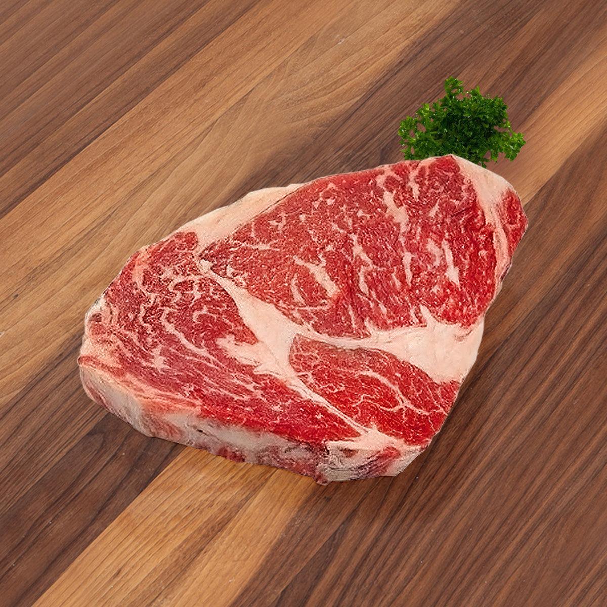 Dry-aged ribeye steak, thick cut with red marbling and white fat cap