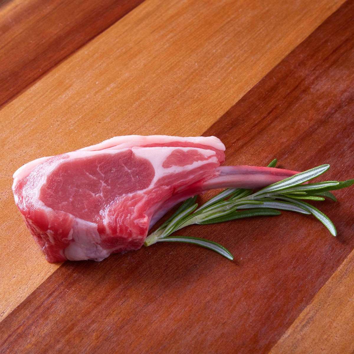 Raw lamb rib chop with rosemary sprigs on it