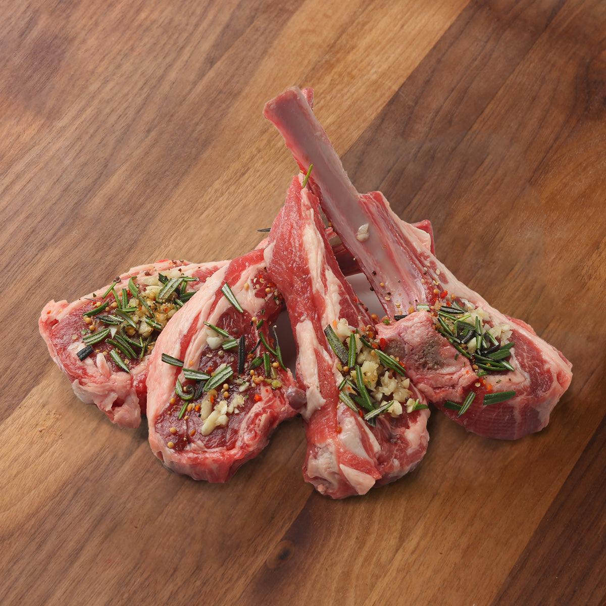 Raw lamb rack chops with rib bones, rosemary and garlic topping