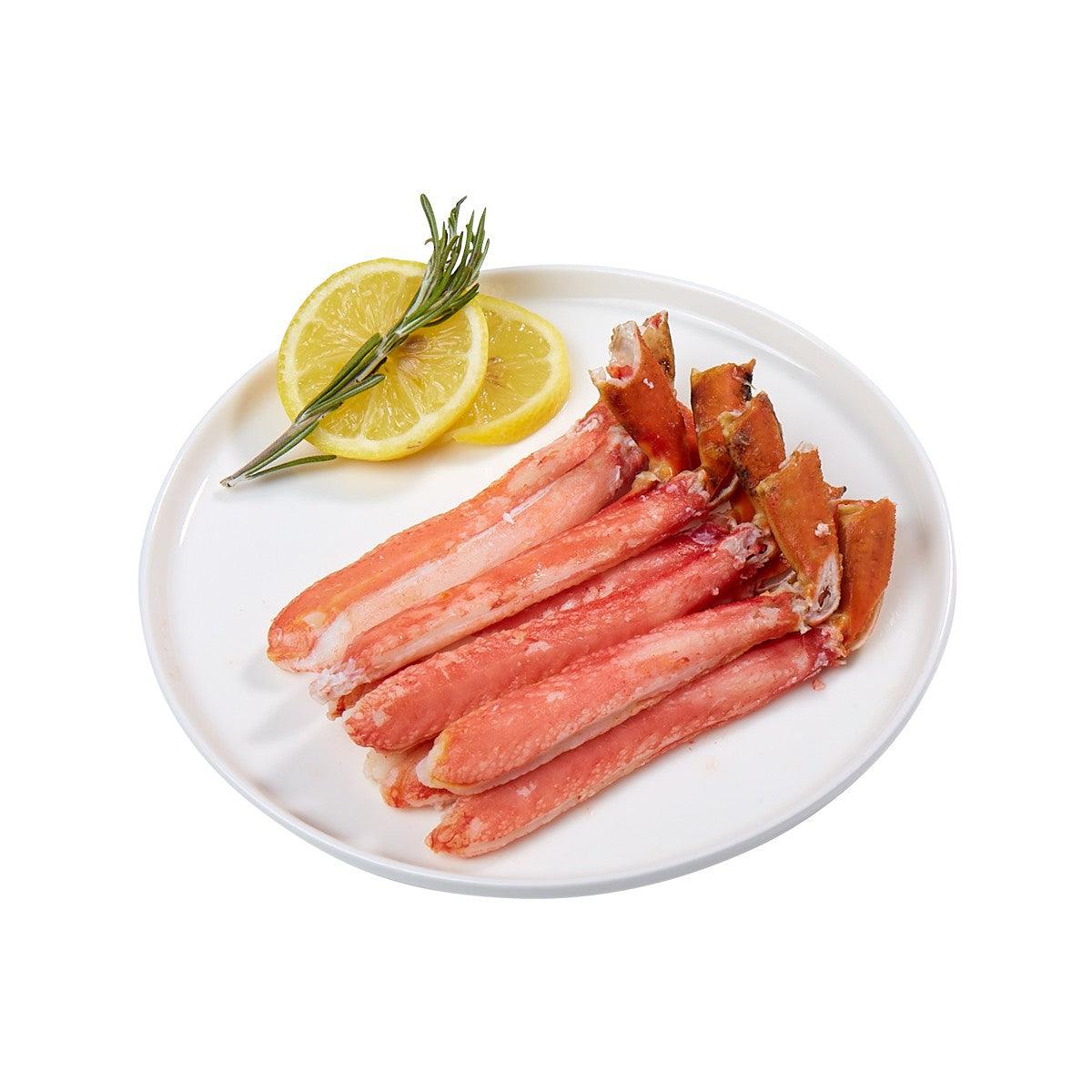 Cooked snow crab legs with lemon wedges and rosemary on white plate