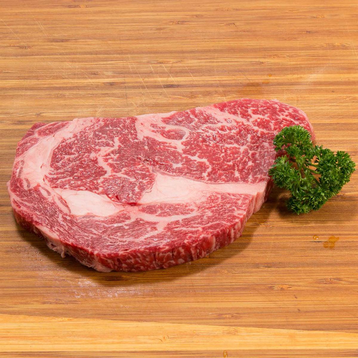 Rib eye steak with visible marbling, garnished with parsley