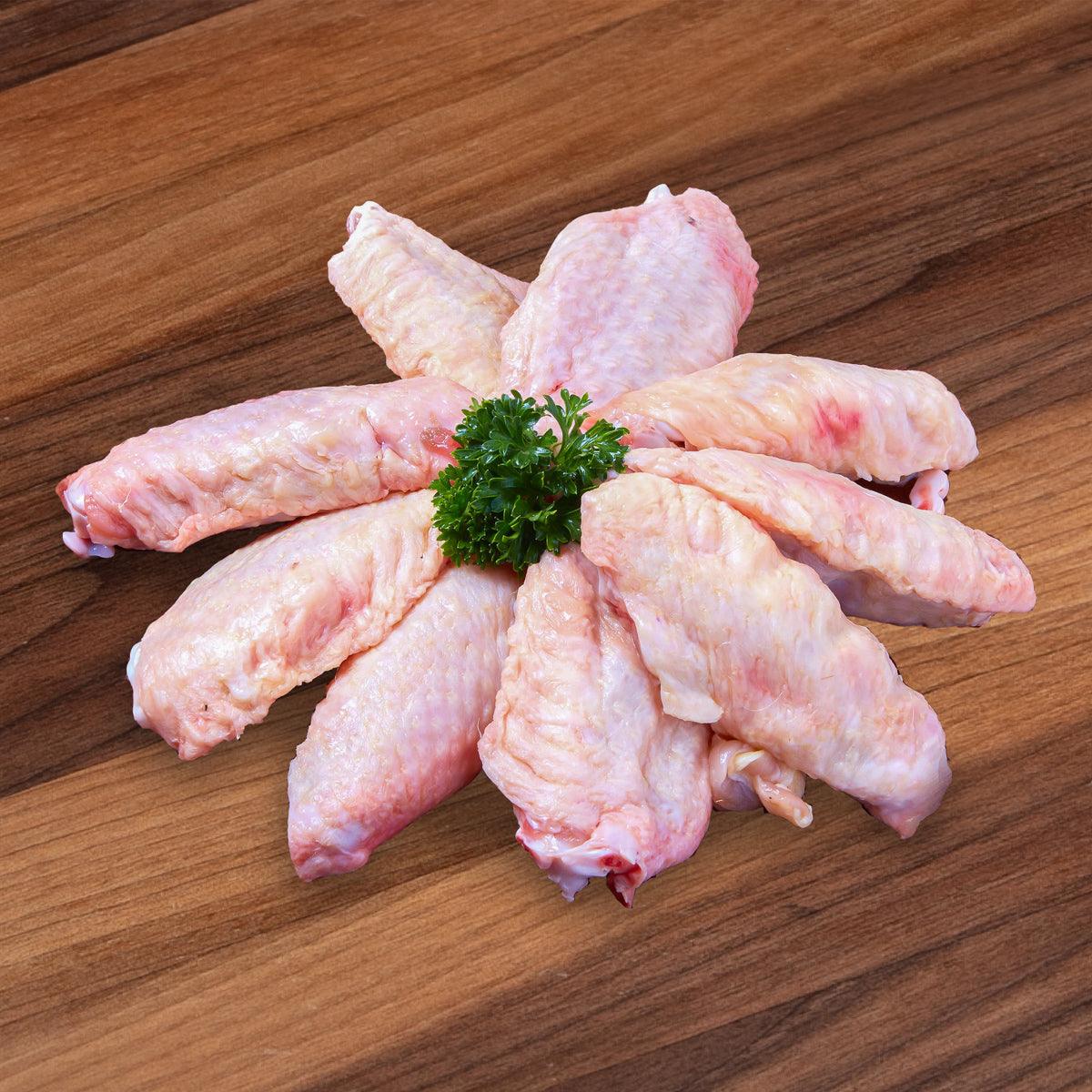 Raw chicken mid-joint wing pieces, pale pink with small parsley garnish