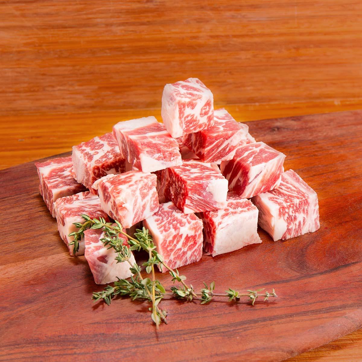 Boneless short rib beef cubes with visible fat marbling and rosemary