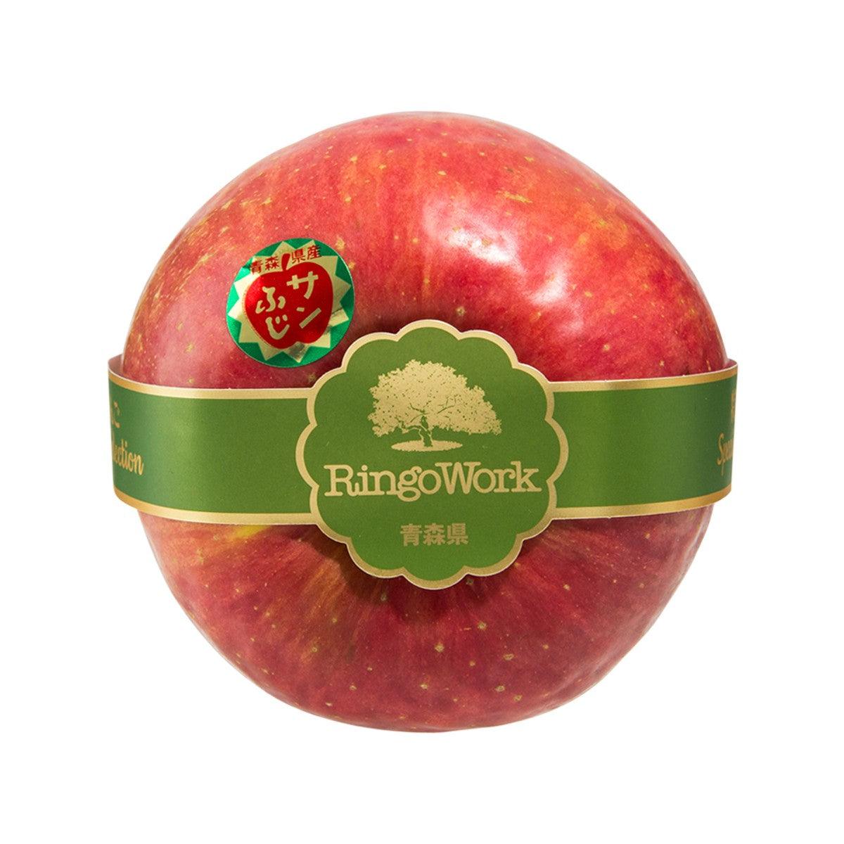 Single Fuji apple with green band label, red skin with light speckles