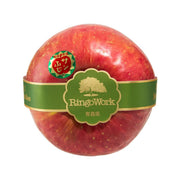 Single Fuji apple with green band label, red skin with light speckles