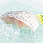 Barramundi fish slice with pale flesh striations, lemon wedge and dill
