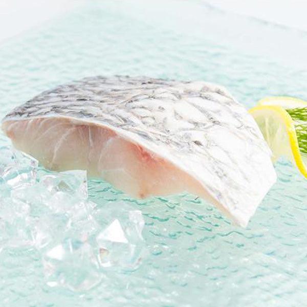 Barramundi fish slice with pale flesh striations, lemon wedge and dill