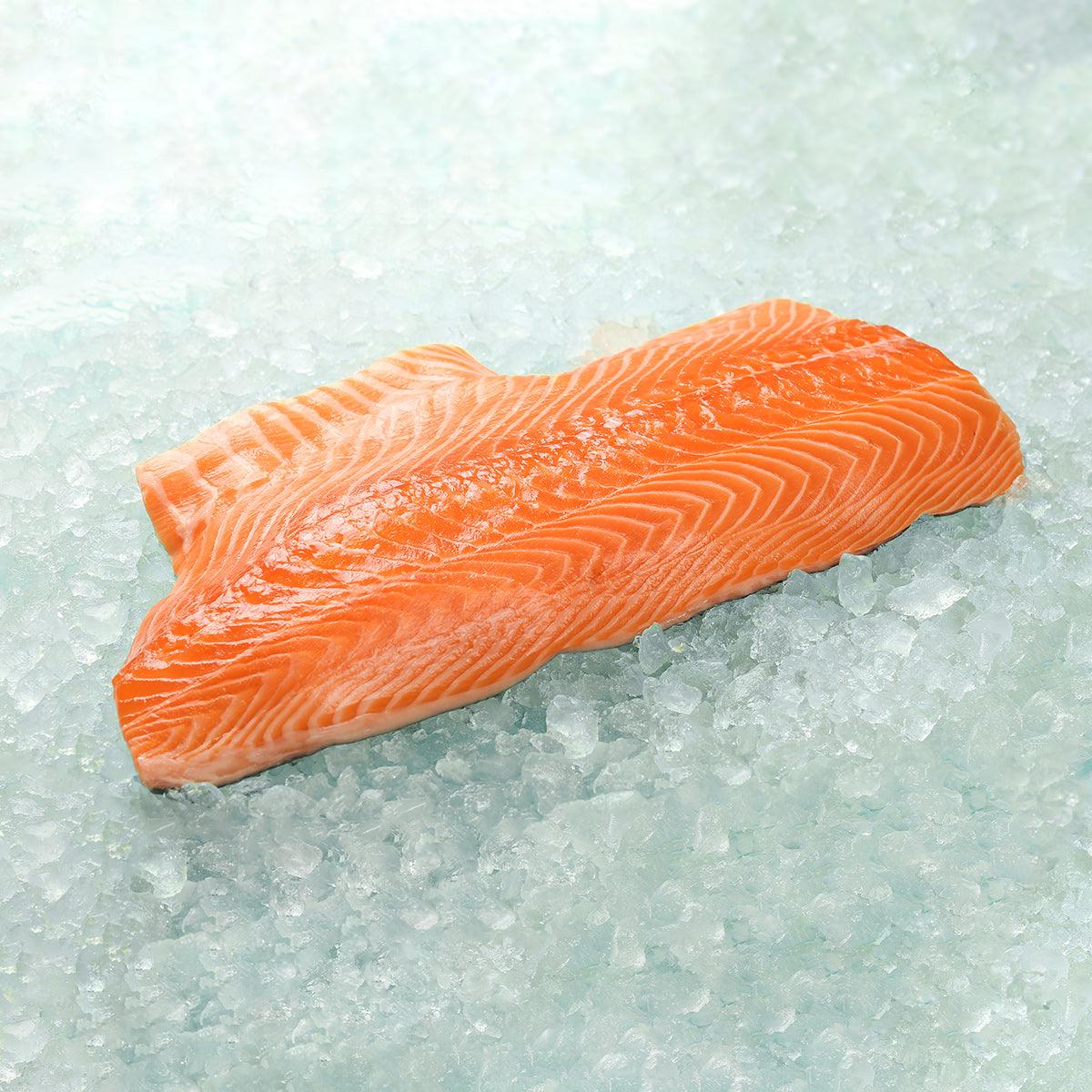 Frozen keta salmon fillet, bright orange raw fish steak on ice.