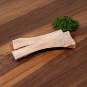 Frozen beef marrow bone pieces, pale bone with reddish marrow and fat