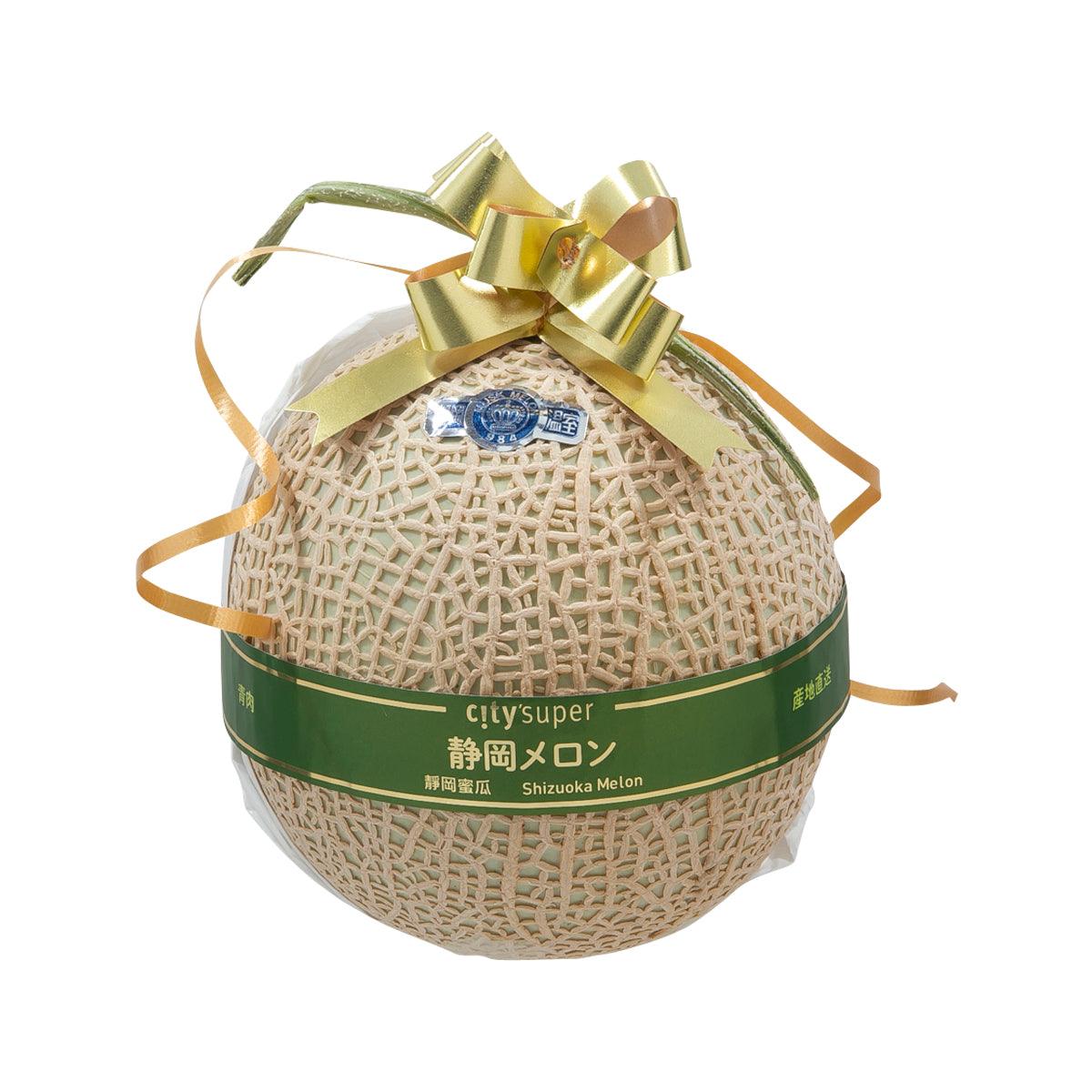 Honey-colored melon in beige mesh net with gold bow ribbon gift wrap