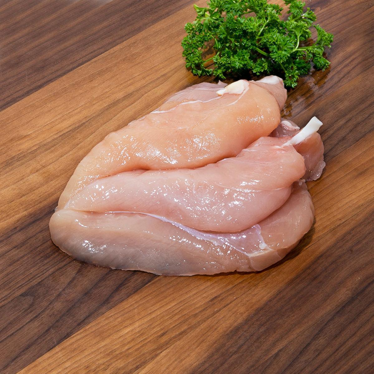 Chilled chicken tenderloin pieces with sprig of parsley, raw pale pink