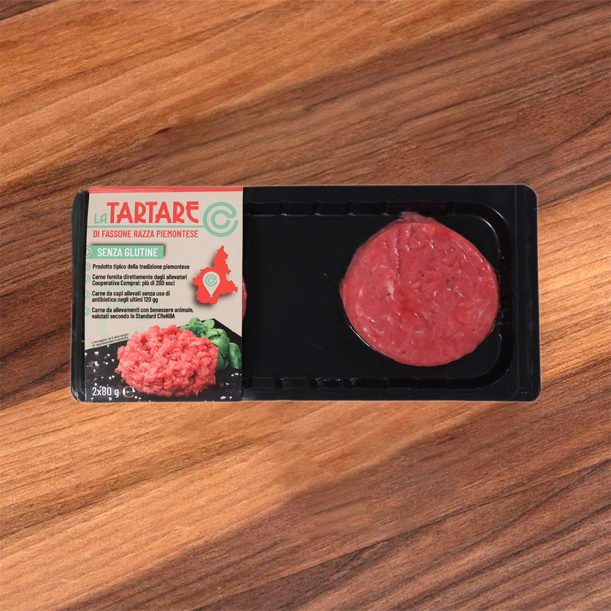 Chilled raw beef tartare in black plastic tray, with label and round red patty.