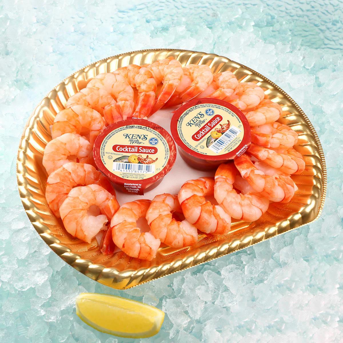 Frozen prawn cocktail platter with curled shrimp, two sauce cups, and lemon wedge