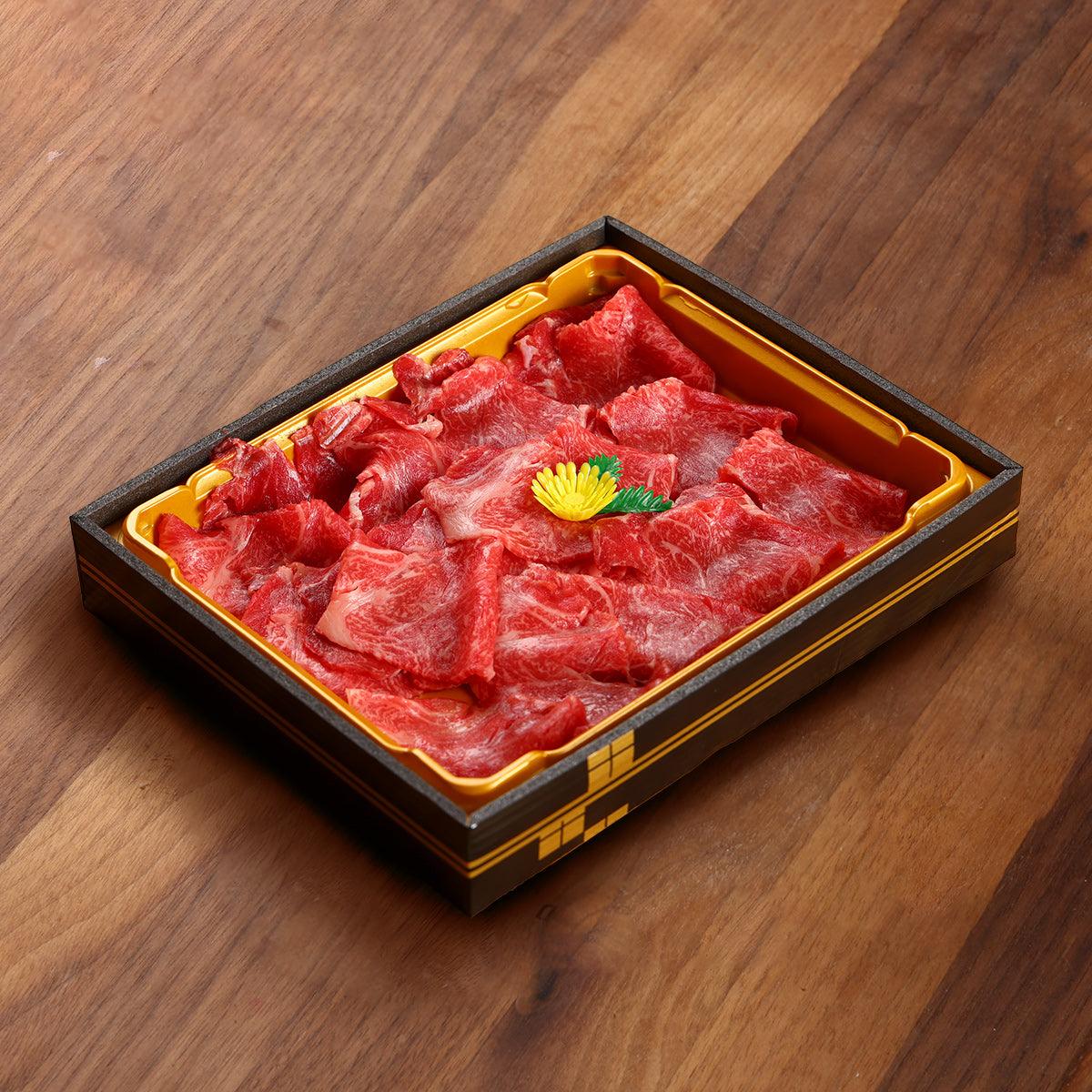 Marbled wagyu beef slices in yellow-lined box tray, red cuts with fat marbling