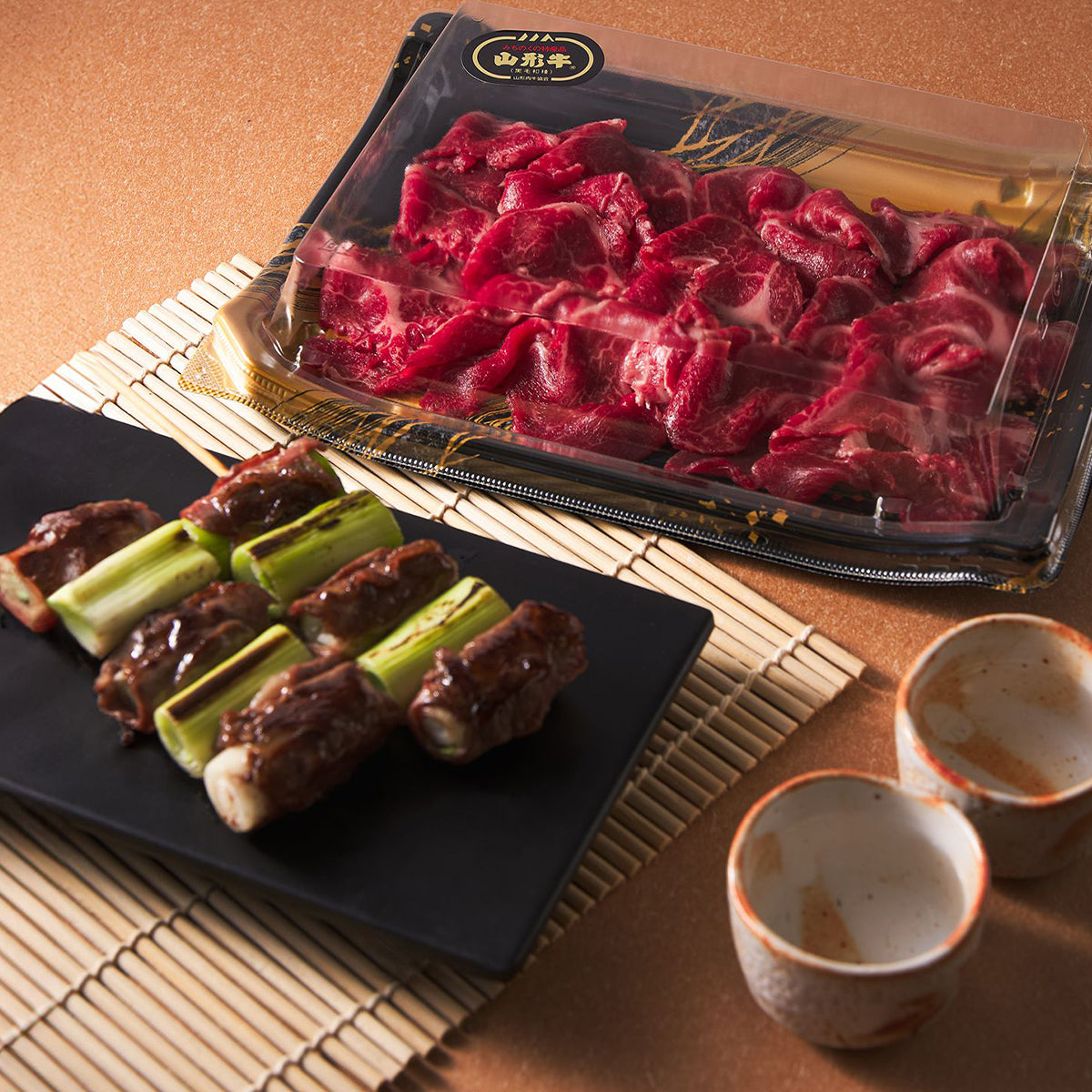 Marbled wagyu beef slices in an open clear container, red chunks for cooking