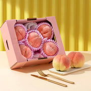 Japanese peach tasting box with open lid, assorted pink peach pieces in paper tray