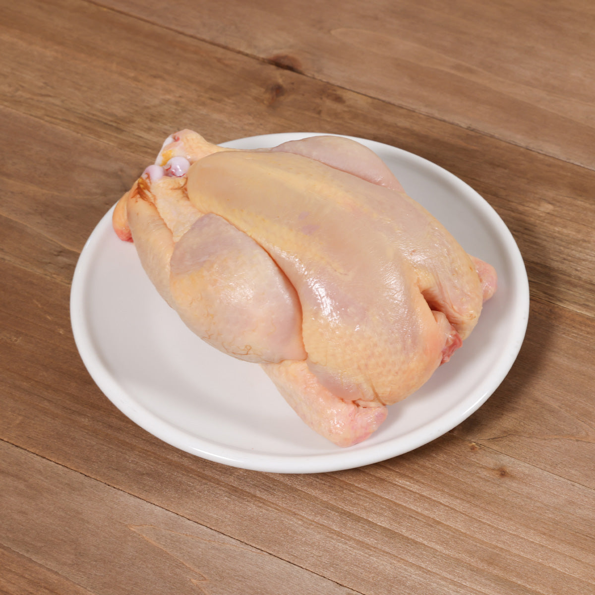 Chilled spring chicken, whole raw poultry on white plate