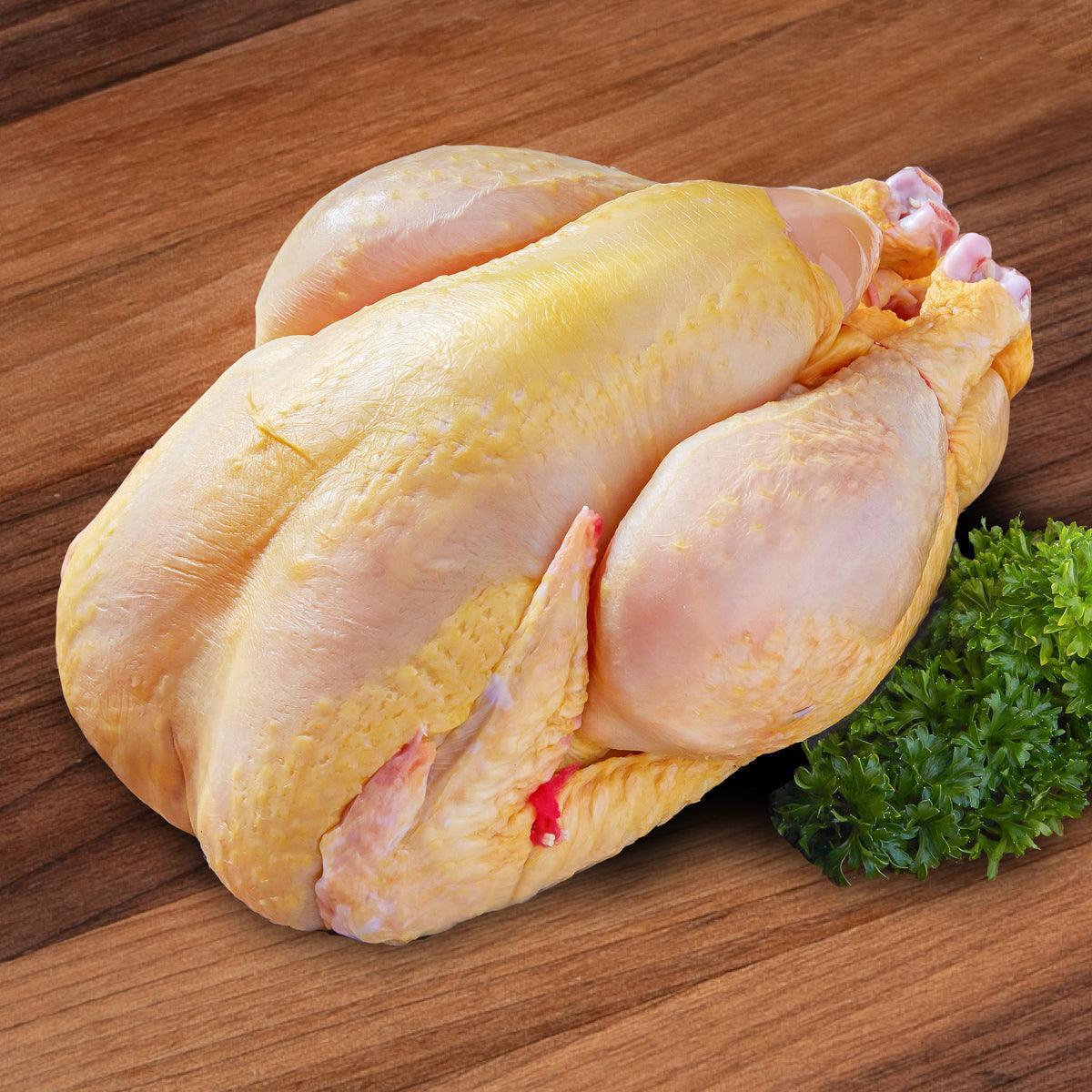 Whole chilled chicken with pale yellow skin and a sprig of parsley