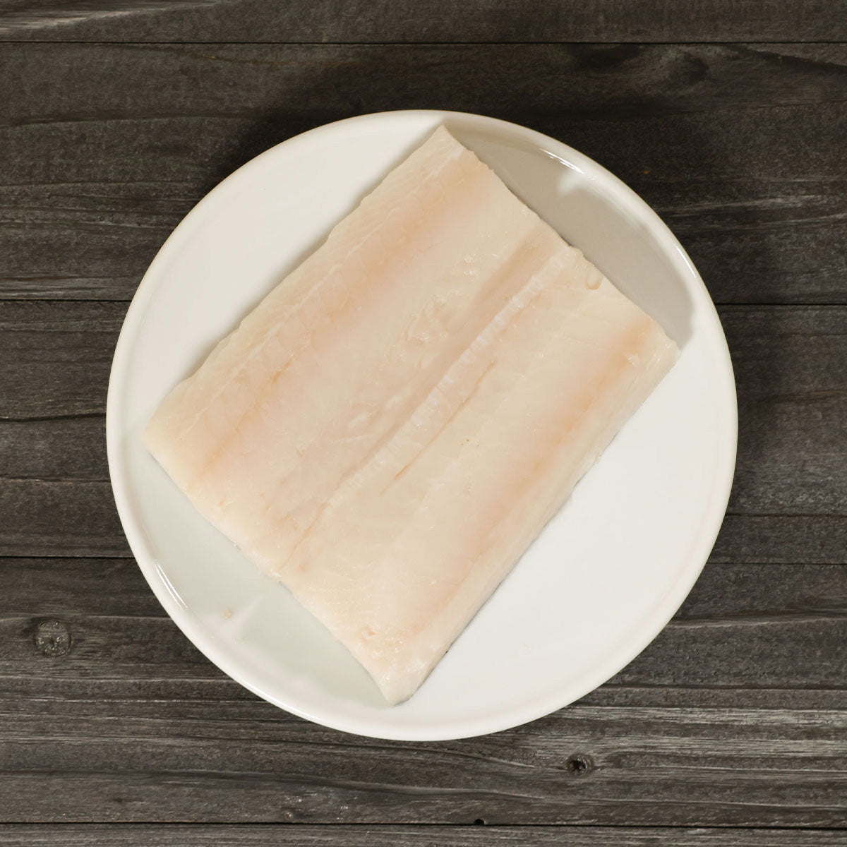 Raw pollack fish fillet on white plate