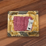 Pack of marbled red wagyu beef yakiniku slices in gold foil tray with label