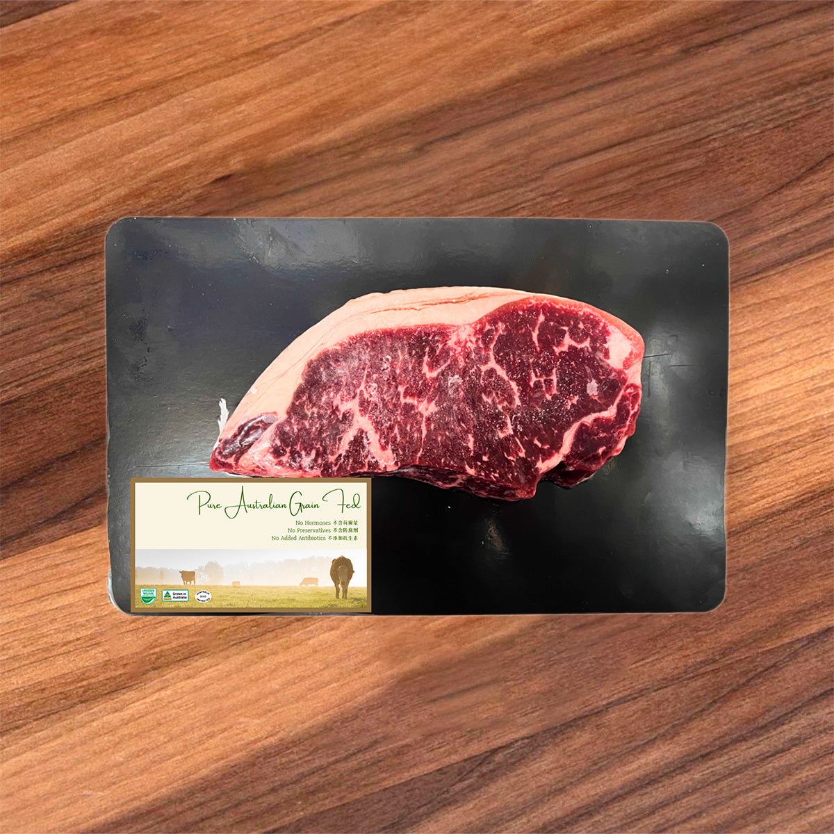 Frozen beef striploin steak on black tray, dark red marbling with pale fat edge