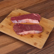 Organic beef steak cuts, two pieces on a wooden cutting board