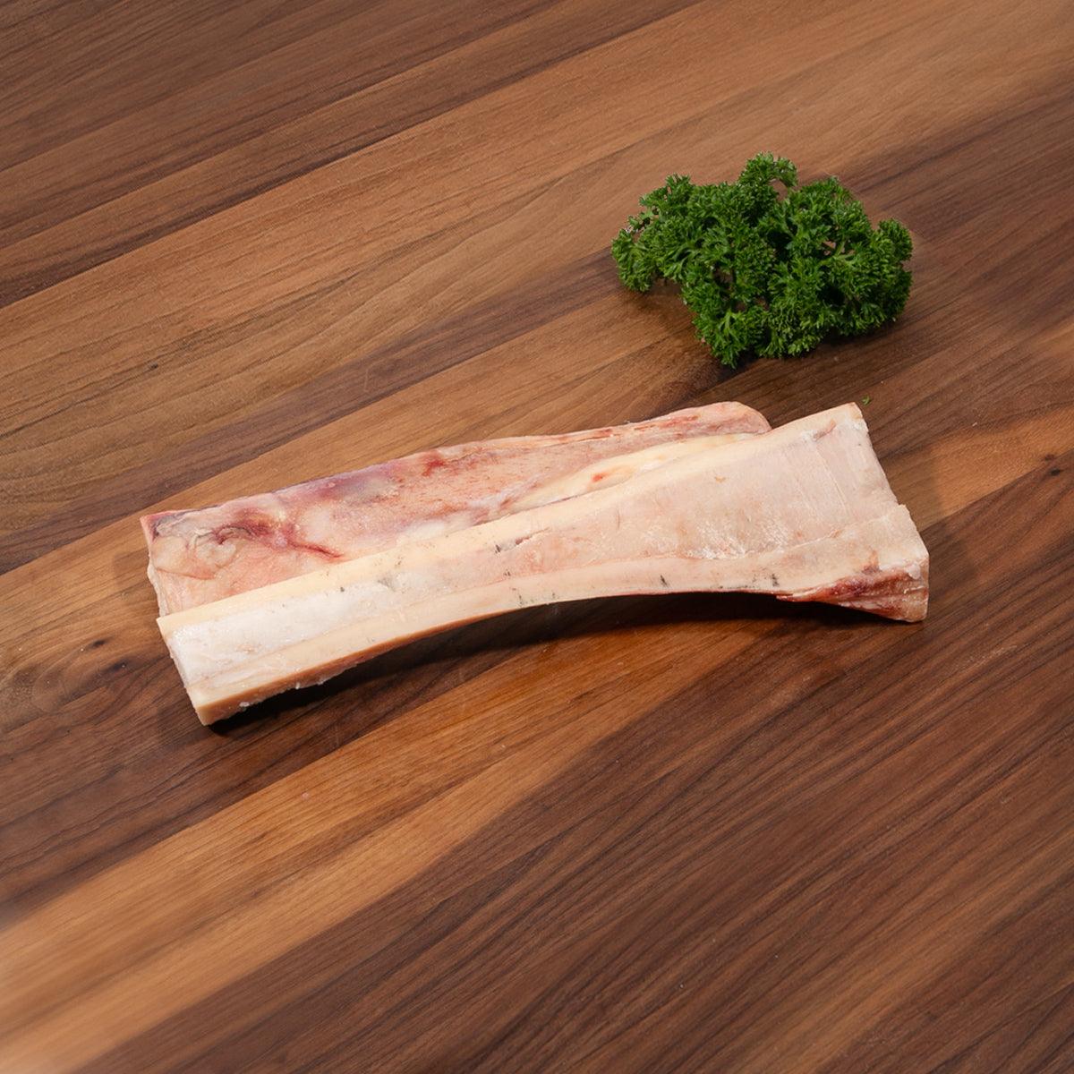 Frozen beef marrow bone, pale bone with red marrow strip