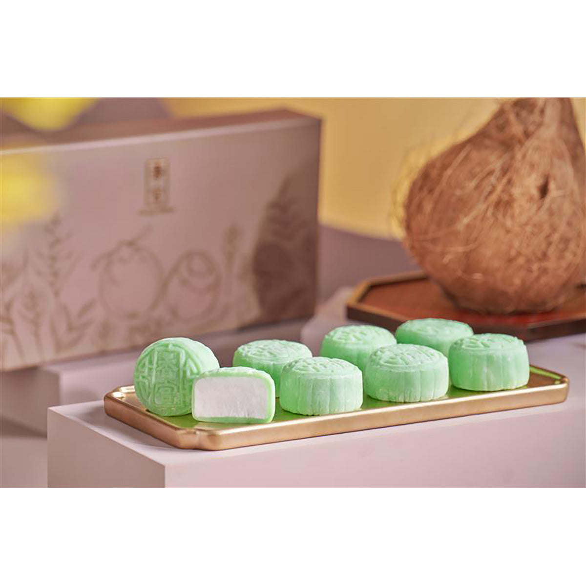 Green snow-skin mooncakes on wooden trays with coconut half