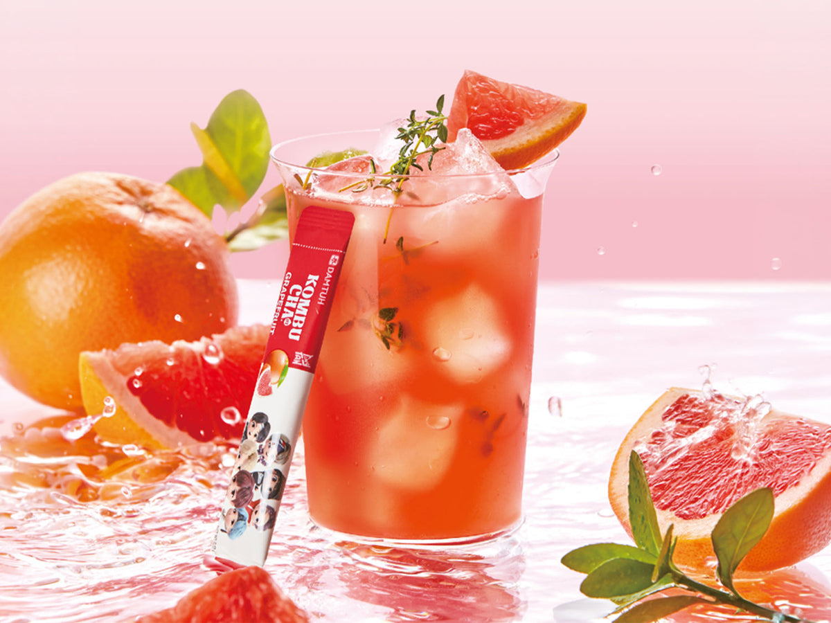 Grapefruit kombucha drink in glass with ice, garnishes, and straw