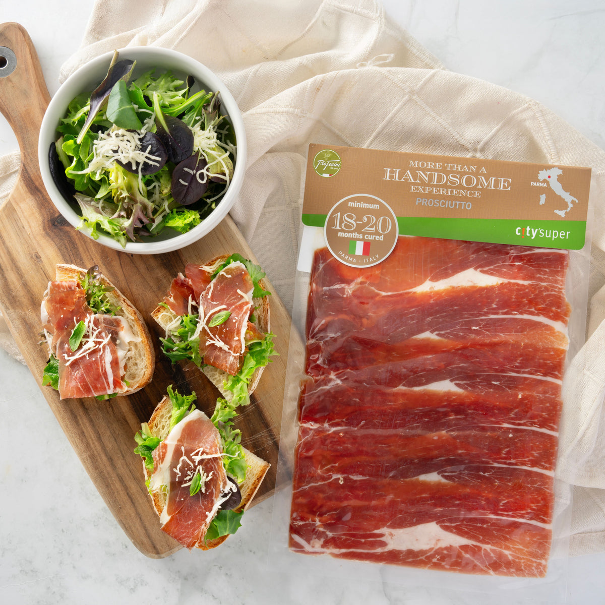 Boneless prosciutto ham with thin marbled slices served with greens, plus sealed pack