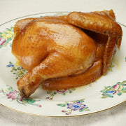 Tea-smoked chicken half with glossy sweet soy sauce on serving plate