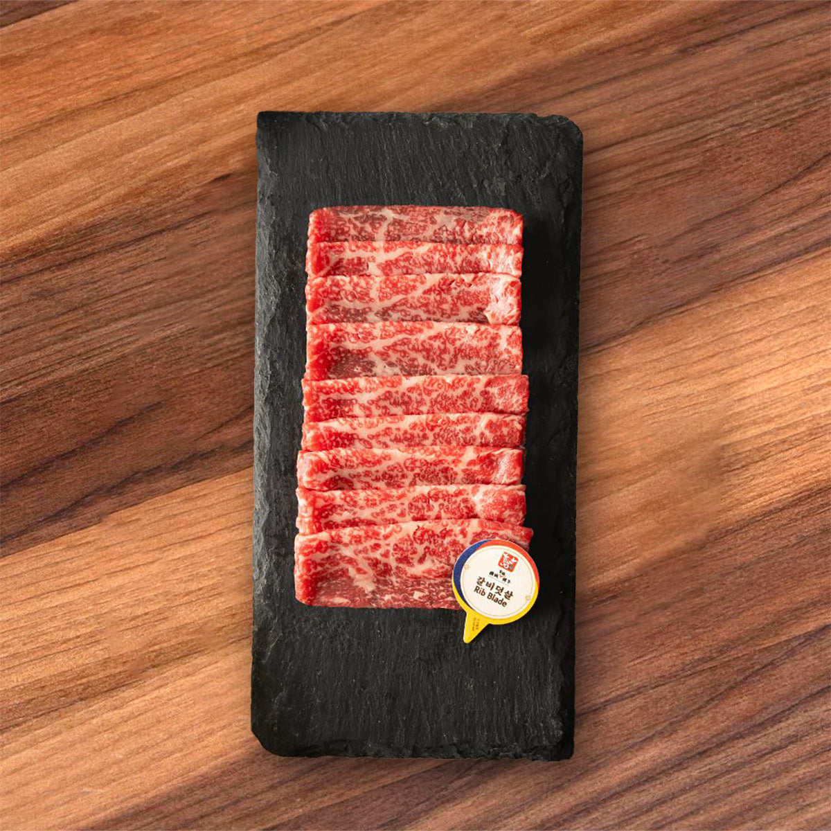 Chilled Hanwoo beef rib blade portion on black slate, marbled red slices