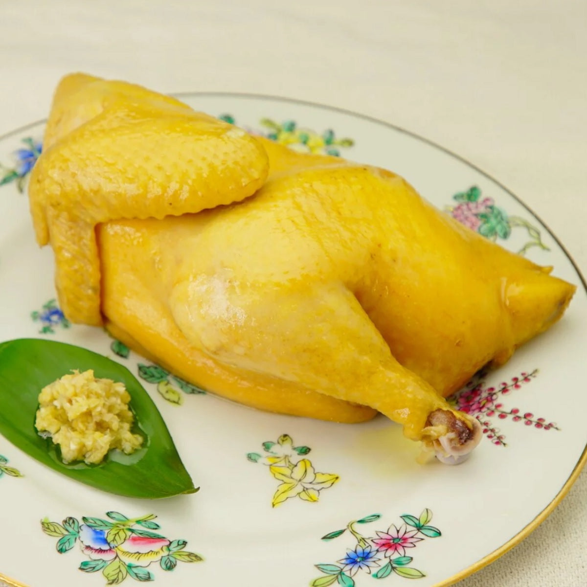 Marinated salty chicken half with minced galangal, plated on a floral dish