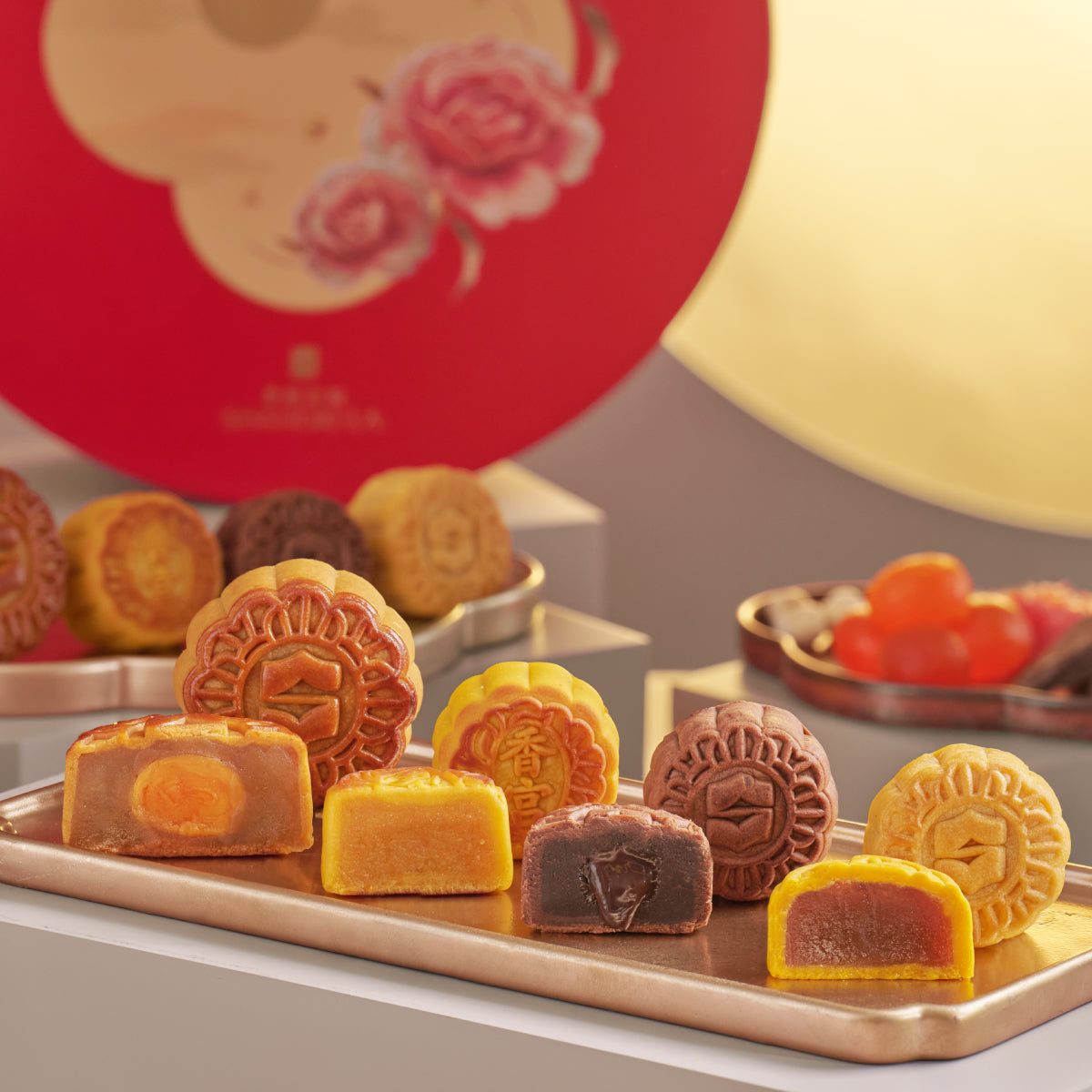 Assorted mooncakes on a tray, including yellow custard and dark lotus pastries