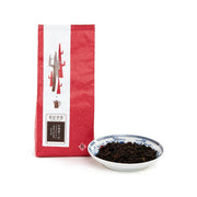 YING KEE Stone Orchid Luk On tea pack with red pouch and bowl of dark tea leaves