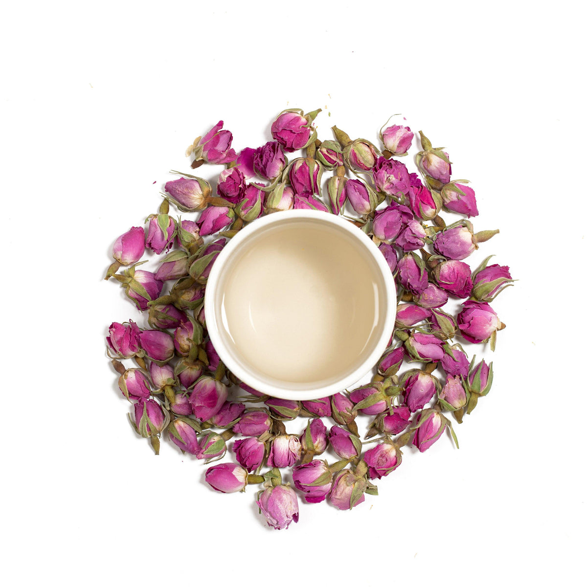Loose pink rose buds tea leaves around an open cup